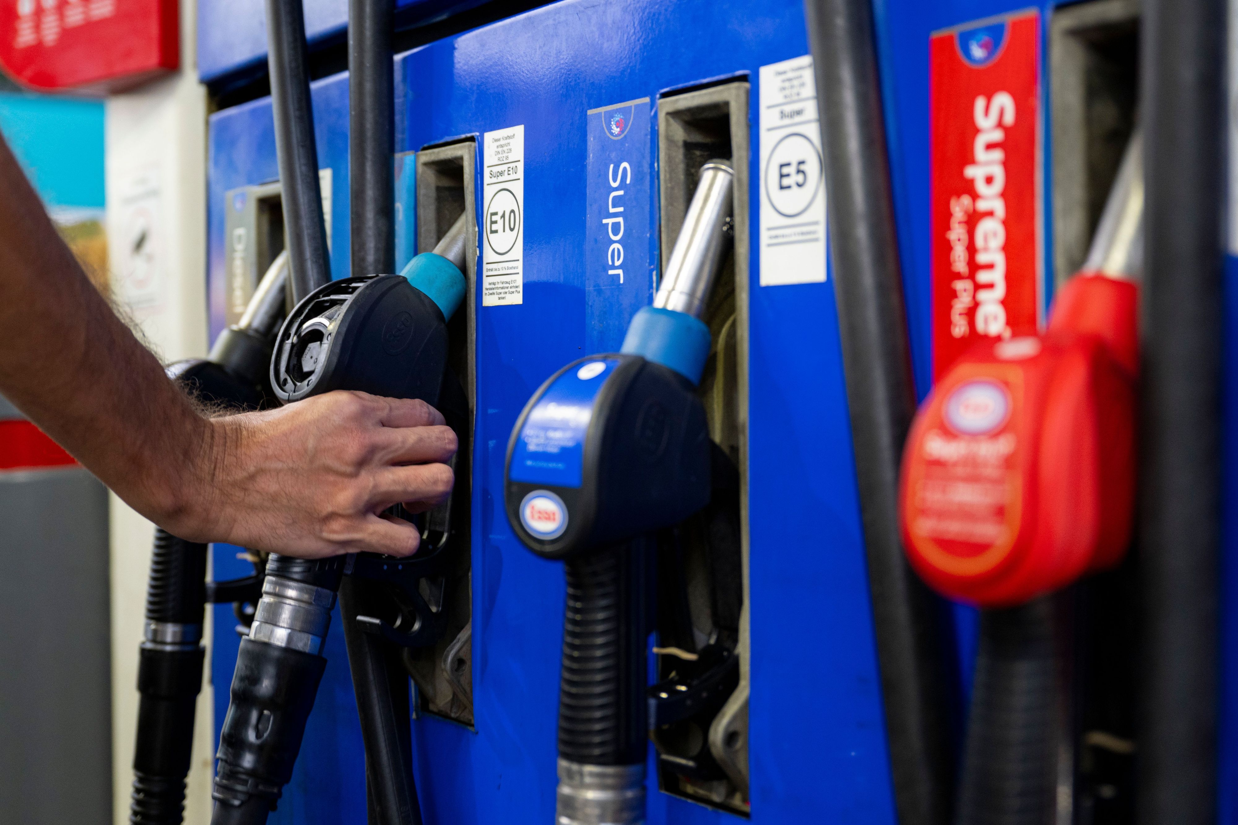 Ein Autofahrer hängt an einer Tankstelle eine Zapfpistole in die Zapfsäule. (Symbolbild)