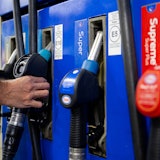 Ein Autofahrer hängt an einer Tankstelle eine Zapfpistole in die Zapfsäule. (Symbolbild)