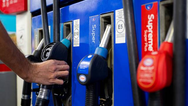 Ein Autofahrer hängt an einer Tankstelle eine Zapfpistole in die Zapfsäule.