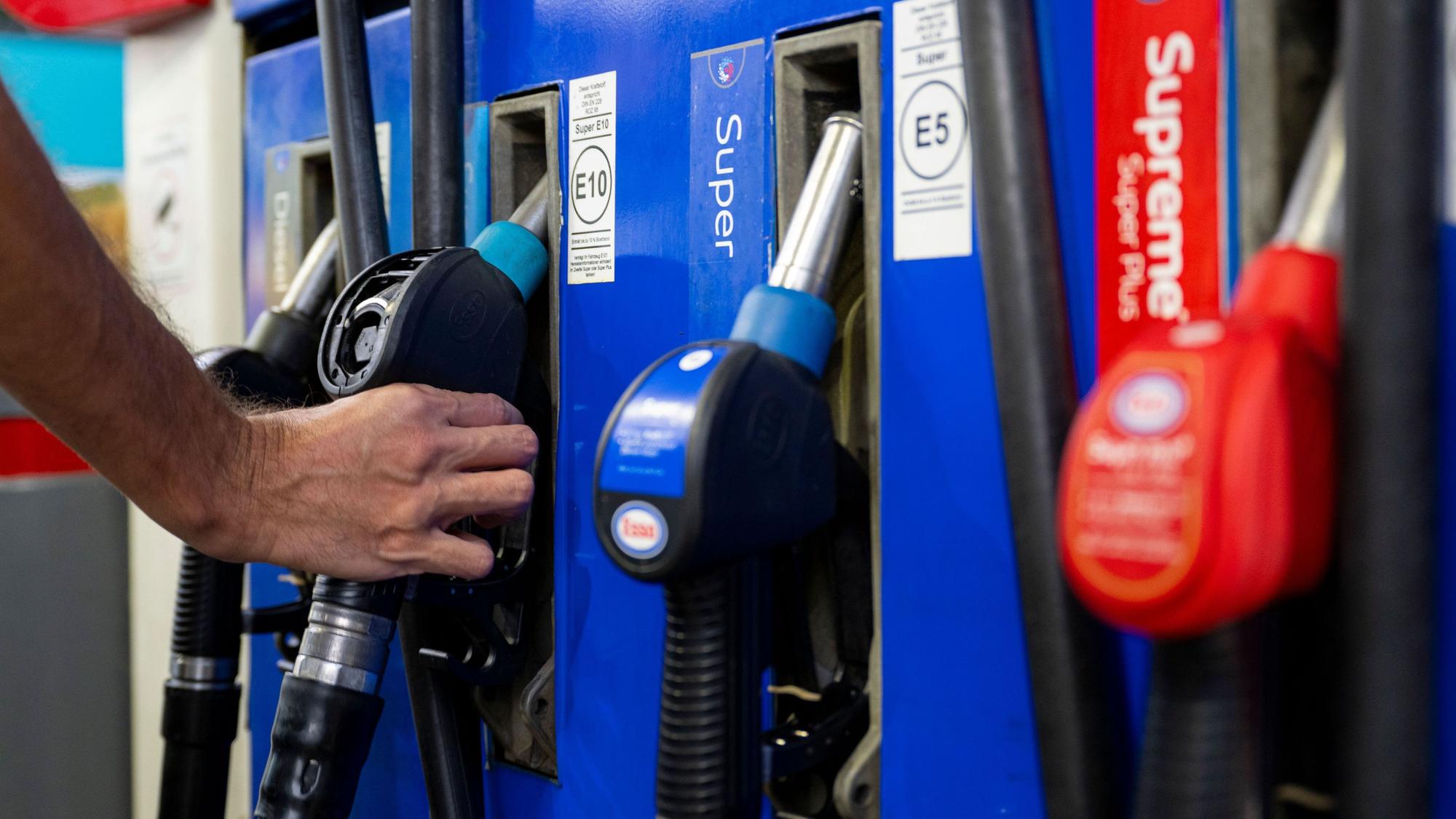 Ein Autofahrer hängt an einer Tankstelle eine Zapfpistole in die Zapfsäule.