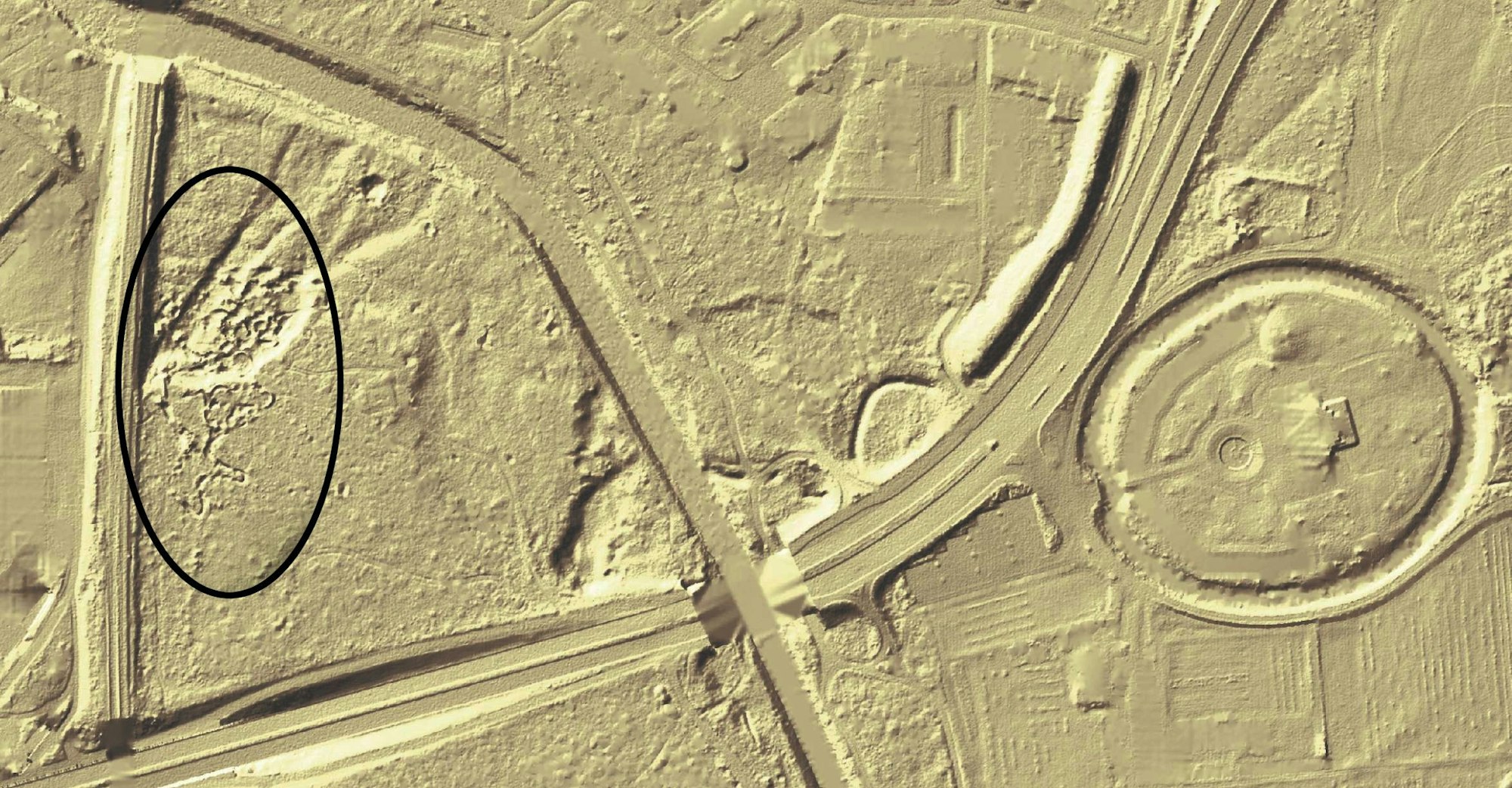 Auf dieser plastischen Darstellung der geländeformen ist die Bahn gut zu sehen. (schwarzes Oval). Zur Orientierung: Die breite Linie am linken Bildrand ist die Eisenbahnstrecke, die linie unten die Gustav-heinemann-Straße, die Gebogene schräge Linie ist die Dhünn und der Kreis rechts der Schlosspark Morsbroich mit dem Wassergraben. der Foto: Geobasis NRW