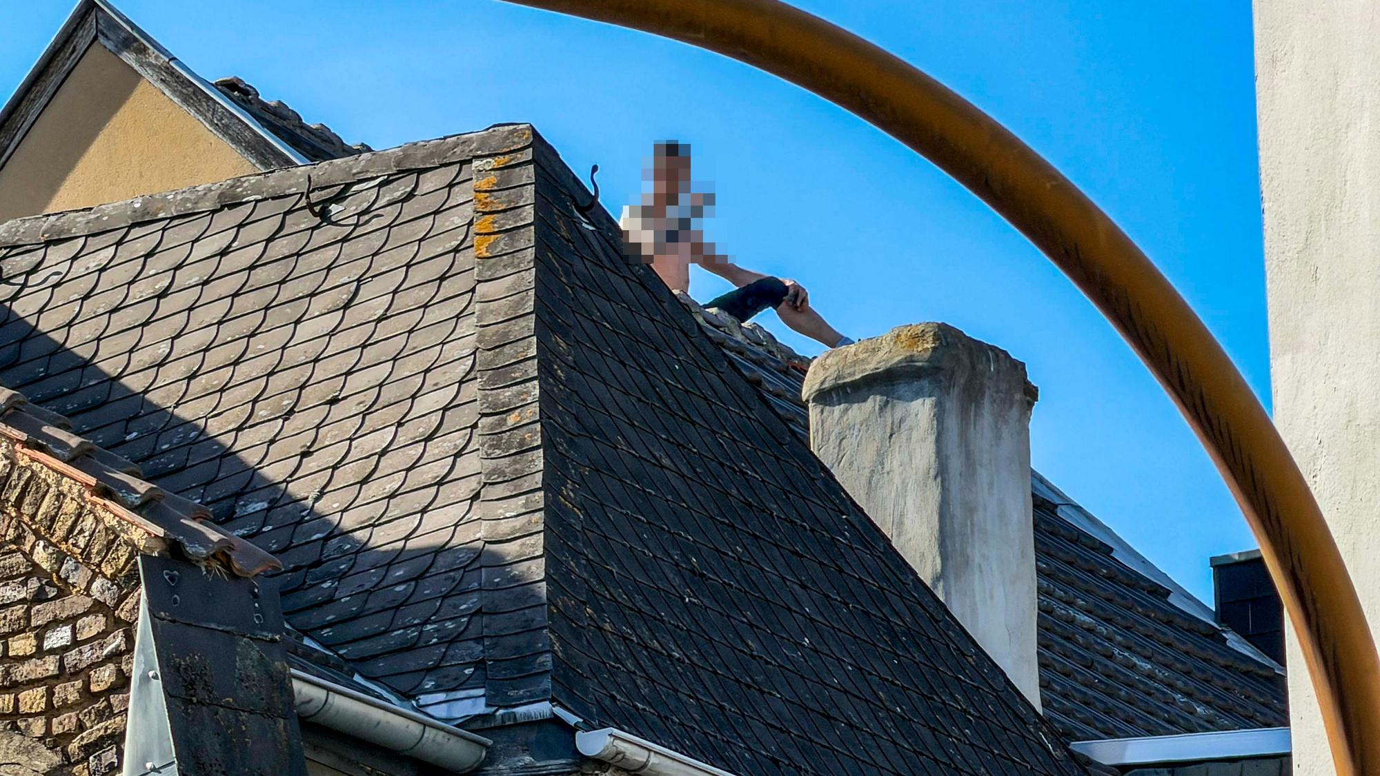 Das Bild zeigt den Mann, wie er auf dem Dach eines Hauses in Euskirchen sitzt.