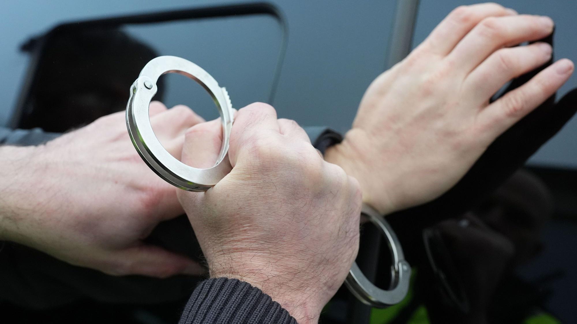 Ein Polizist legt einem Mann Handschellen an.
