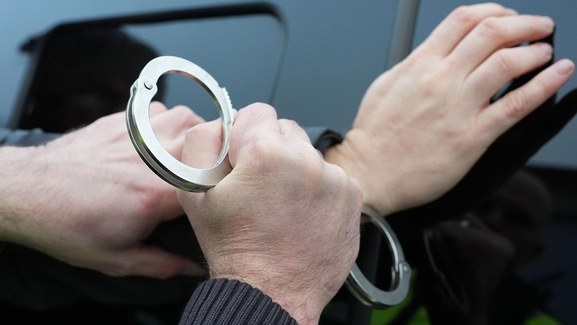 Ein Polizist legt einem Mann Handschellen an.