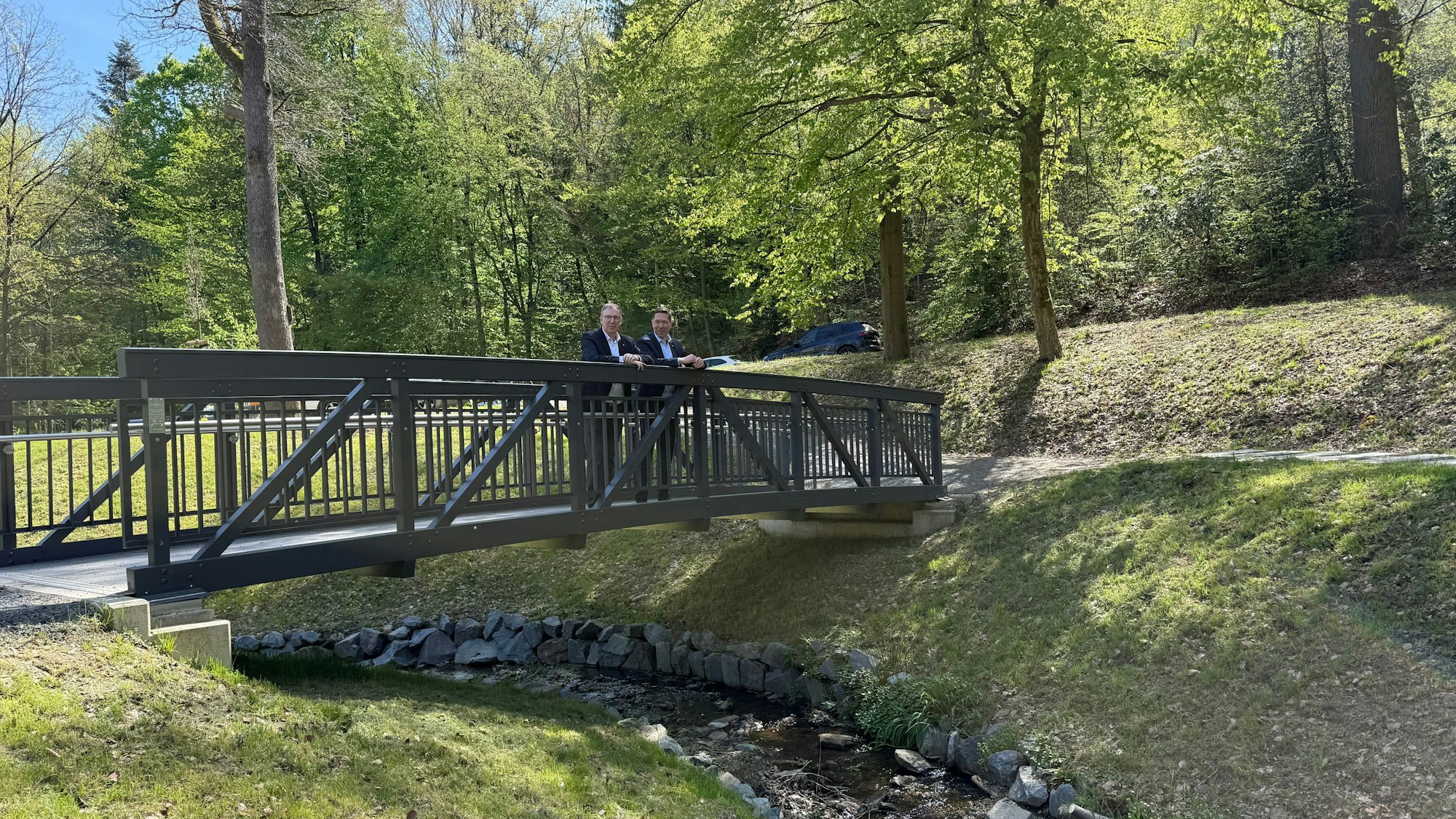 Raoul Halding-Hoppenheit und Hefner stehen auf der neuen Brücke im Hömicker Bachgarten.