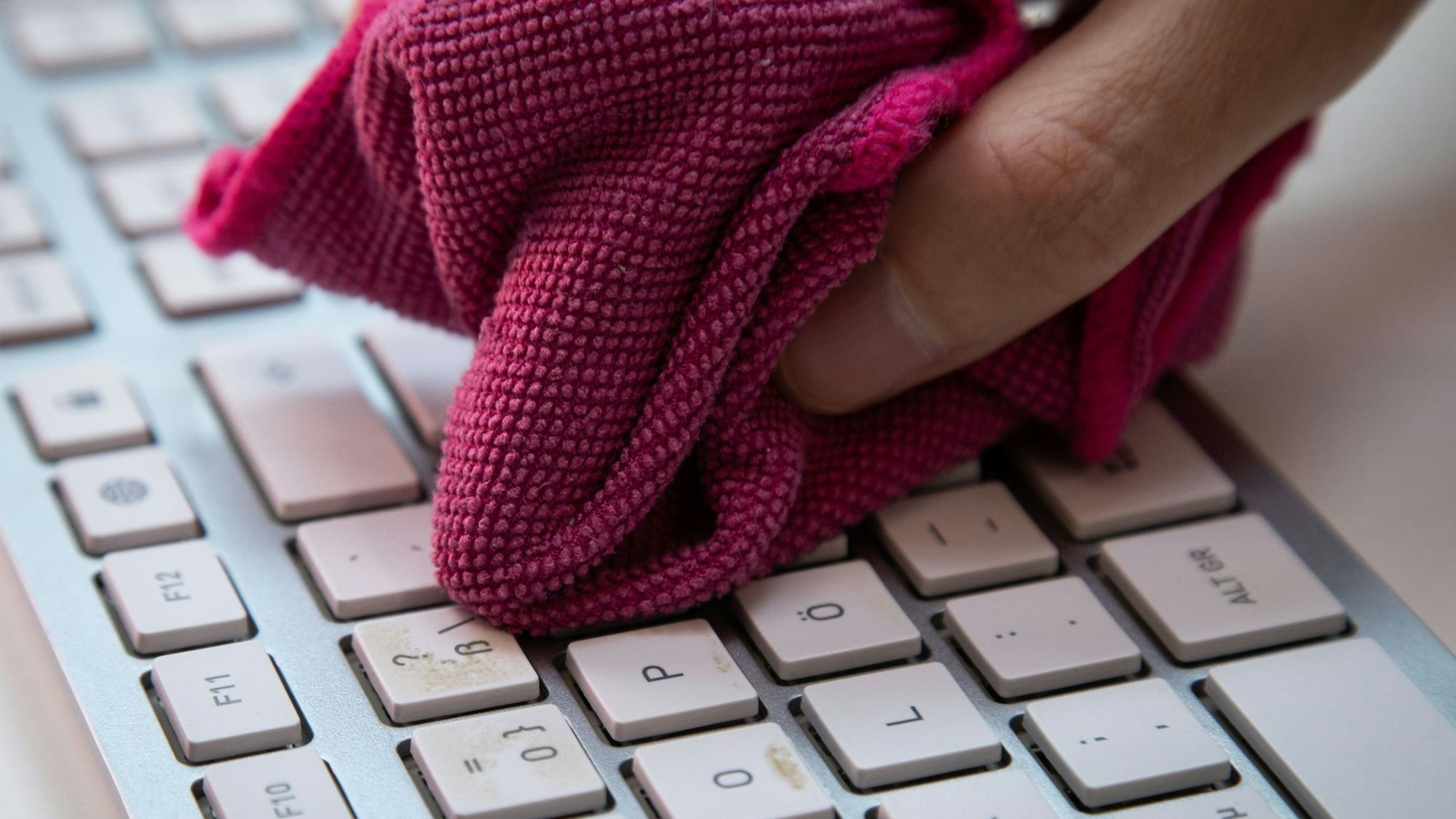 Ein Mann reinigt eine Tastatur mit einem Mikrofasertuch