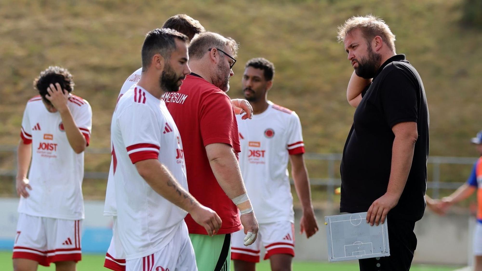 Sebastian Reisenauer steht am Spielfeldrand, In der Hand hält er eine kleine Taktiktafel.