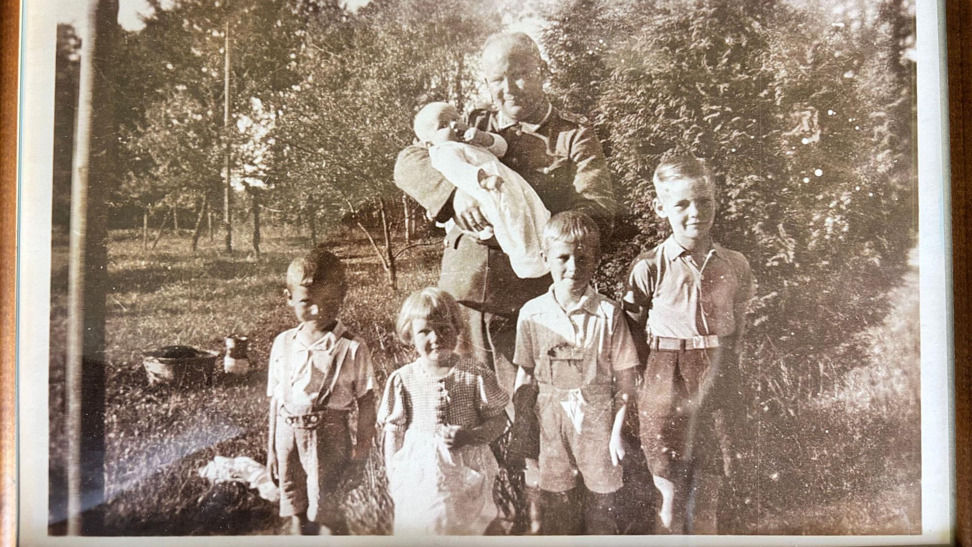Das Schwarz-Weiß-Foto zeigt einen Mann mit fünf Kindern. Das Baby hält er auf dem Arm, die vier Kinder stehen vor ihm.