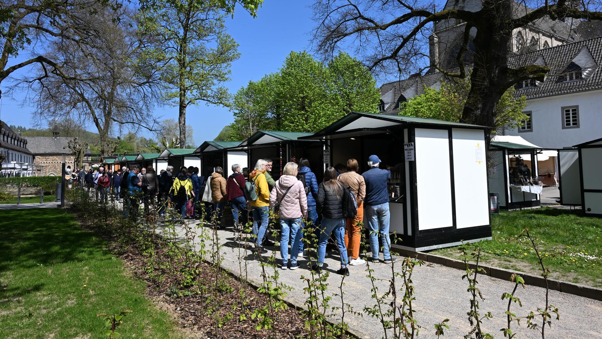 Besucher laufen an Marktständen vorbei.