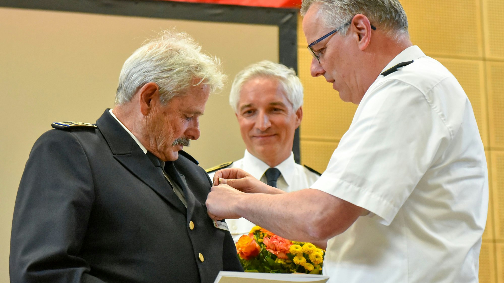 Auf dem Bild ist ein Feuewehrmann zu sehen, der geehrt wird.