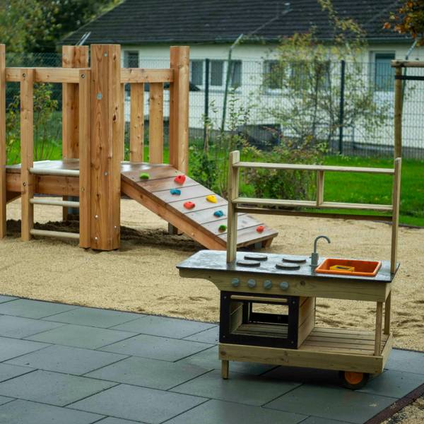 Eine Spielküche und ein Klettergerüst im Außenbereich einer Kita.
