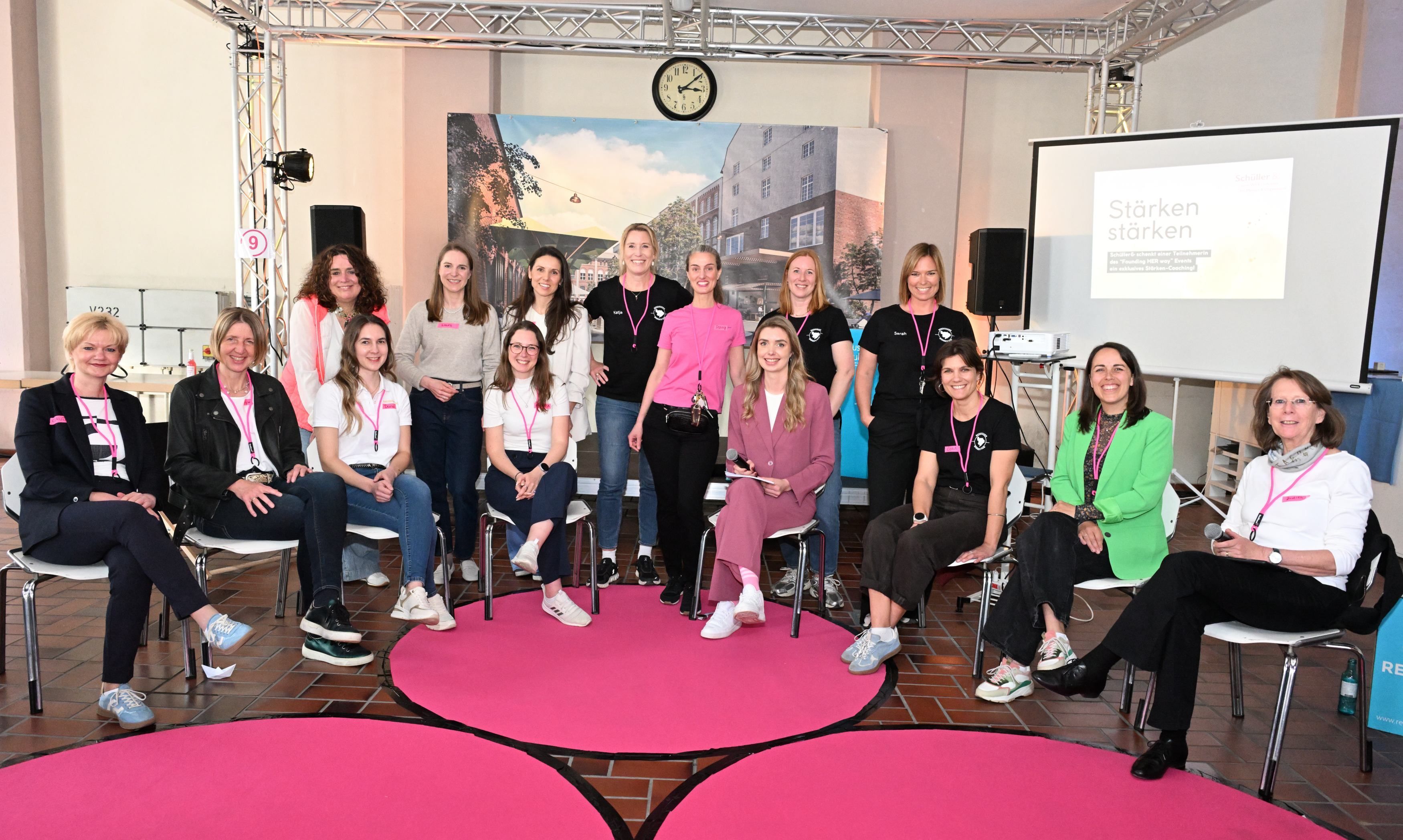 Eine Gruppe Frauen sitzt im Halbkreis und lächelt in Richtung Kamera.