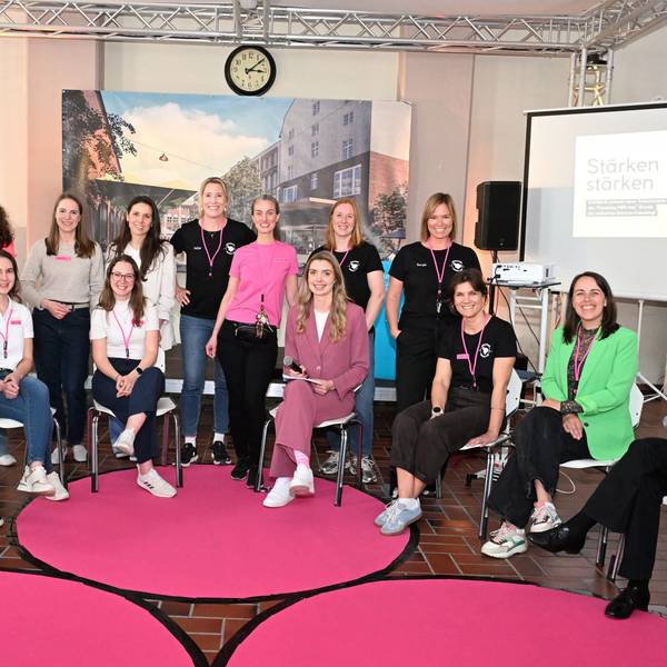 Eine Gruppe Frauen sitzt im Halbkreis und lächelt in Richtung Kamera.
