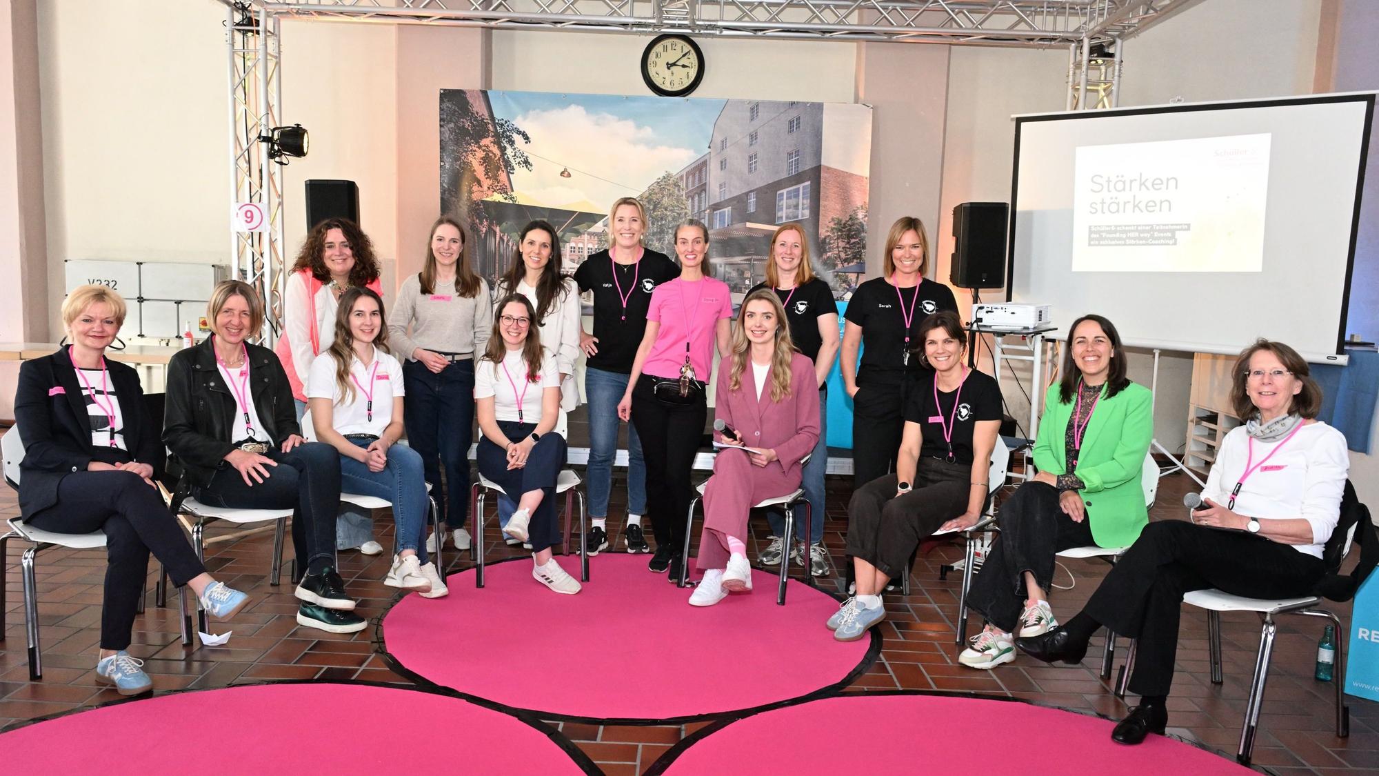 Eine Gruppe Frauen sitzt im Halbkreis und lächelt in Richtung Kamera.