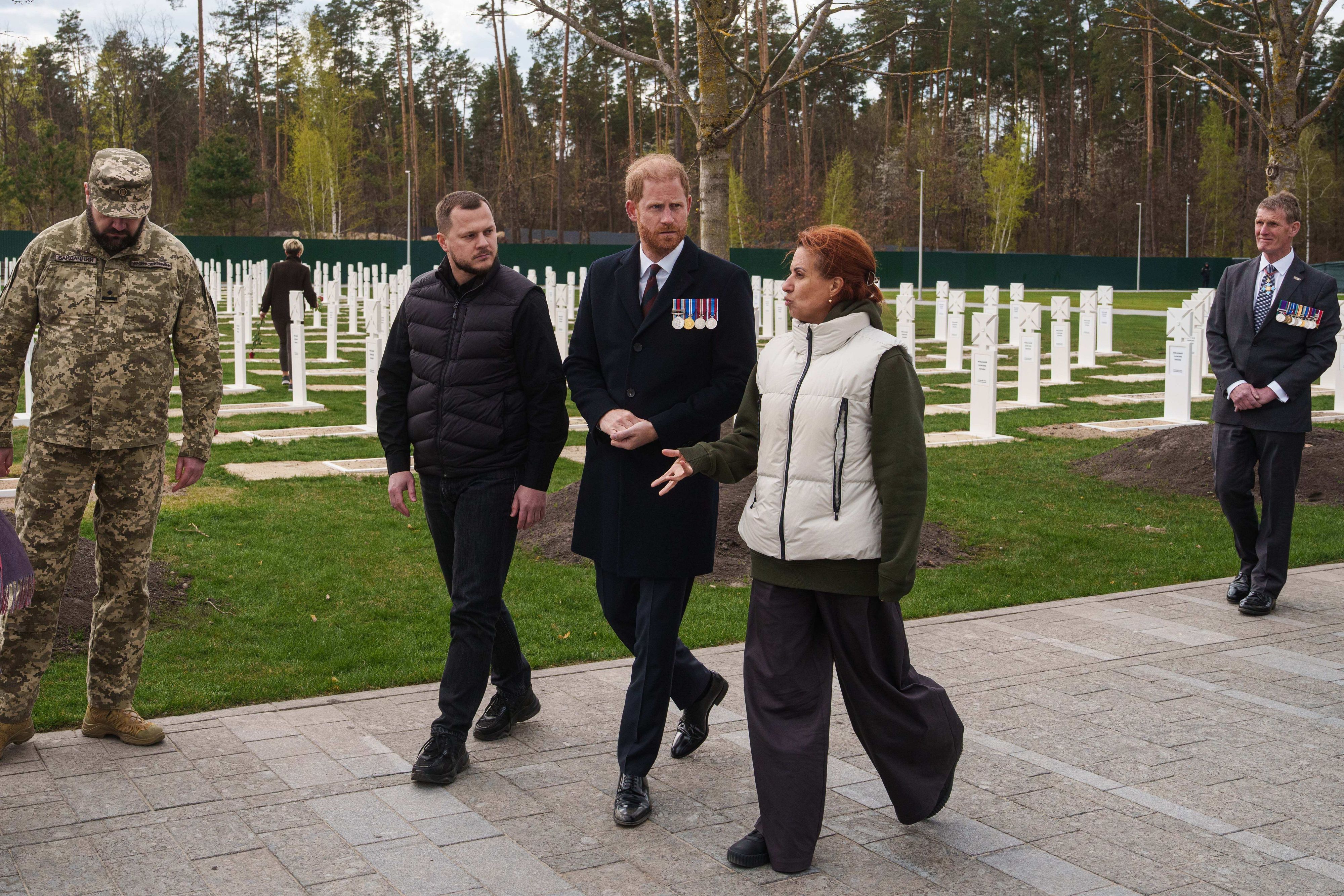Prinz Harry (M) und Natalia Kalmykova (r), ukrainische Veteranenministerin, besuchen einen Soldatenfriedhof in der Nähe von Kiew.