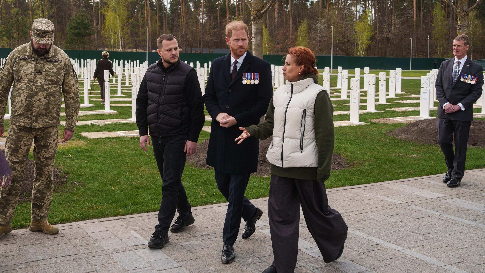 Prinz Harry (M) und Natalia Kalmykova (r), ukrainische Veteranenministerin, besuchen einen Soldatenfriedhof in der Nähe von Kiew.