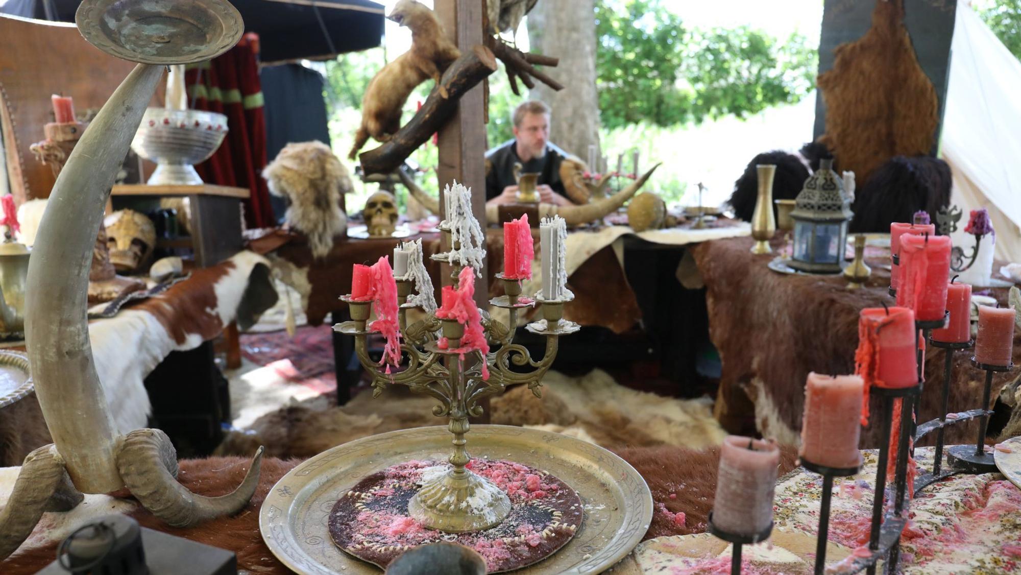 Tische mit Kerzenständern, Bechern und Schalen sowie Fellen als Tischdecke.