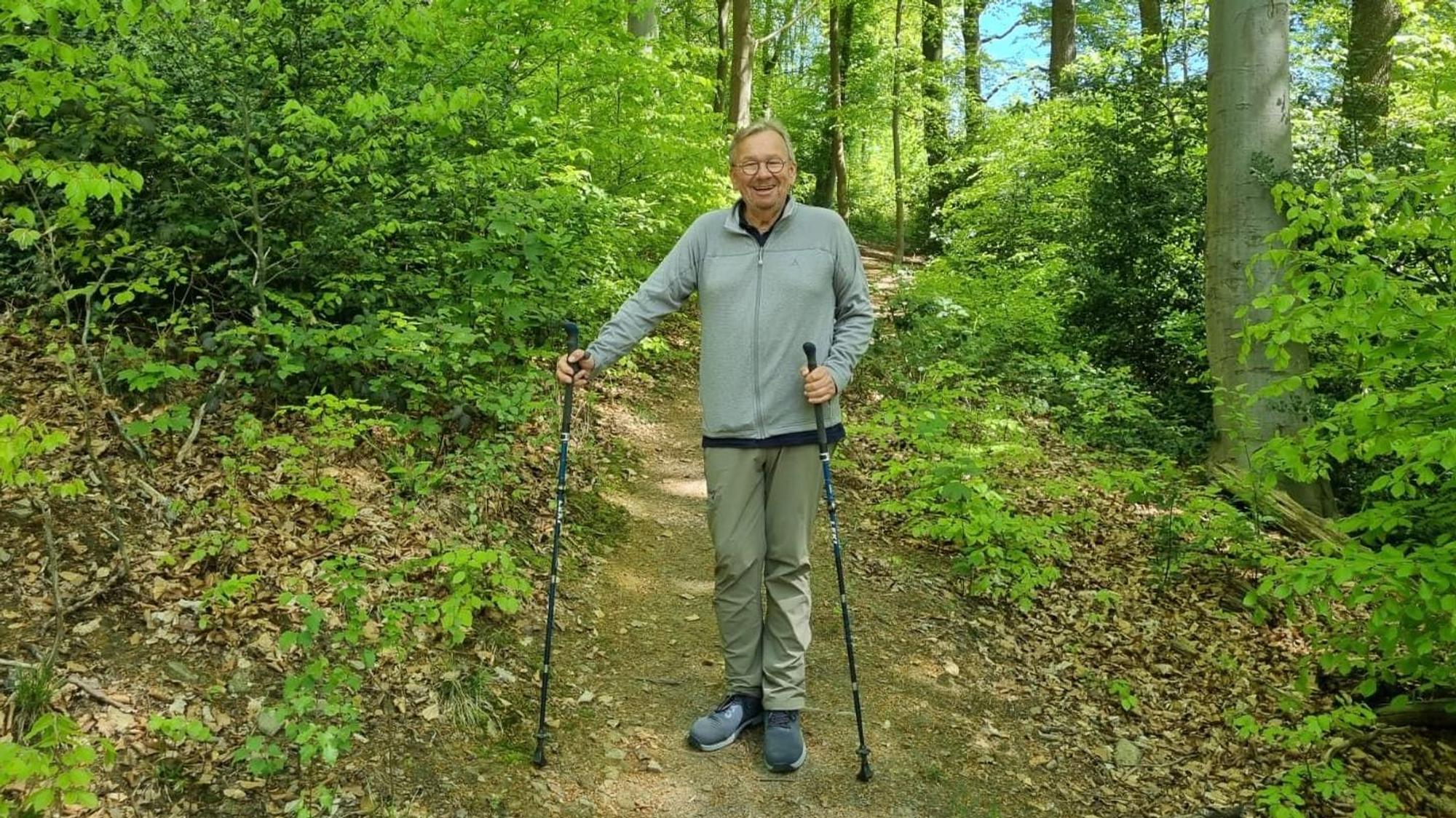 Bernd Stelter steht mit Wanderstöcken im Wald.