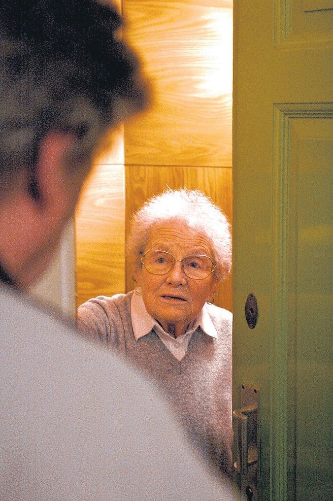 Ein Mann steht an einer Wohnungstür vor einer Seniorin.