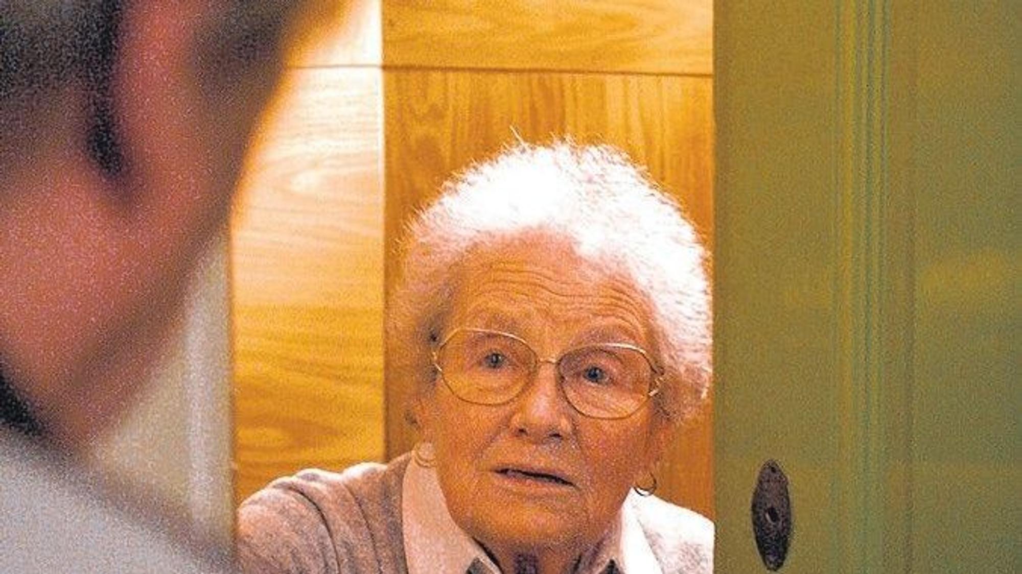 Ein Mann steht an einer Wohnungstür vor einer Seniorin.