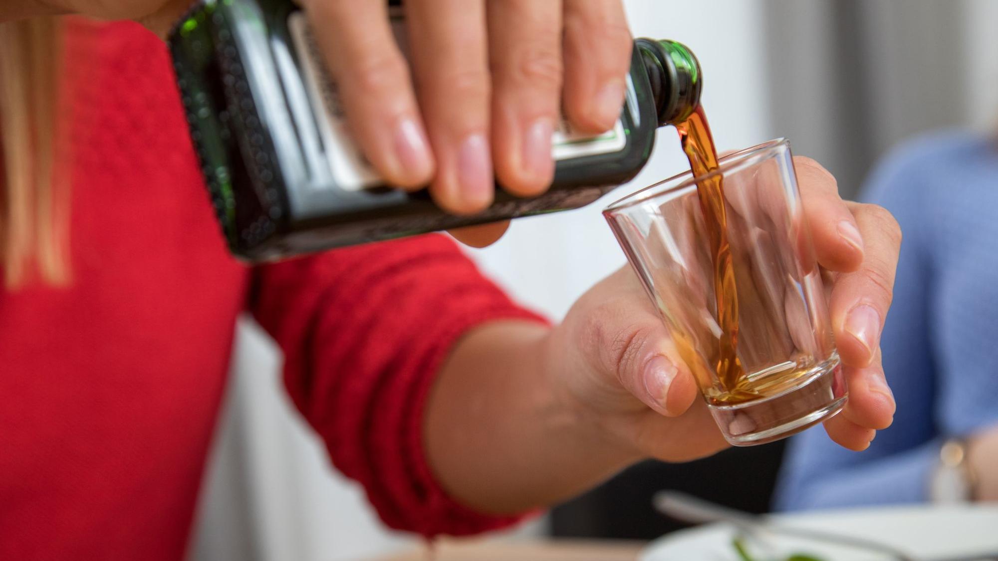 Frau schenkt ein Glas Schnaps ein