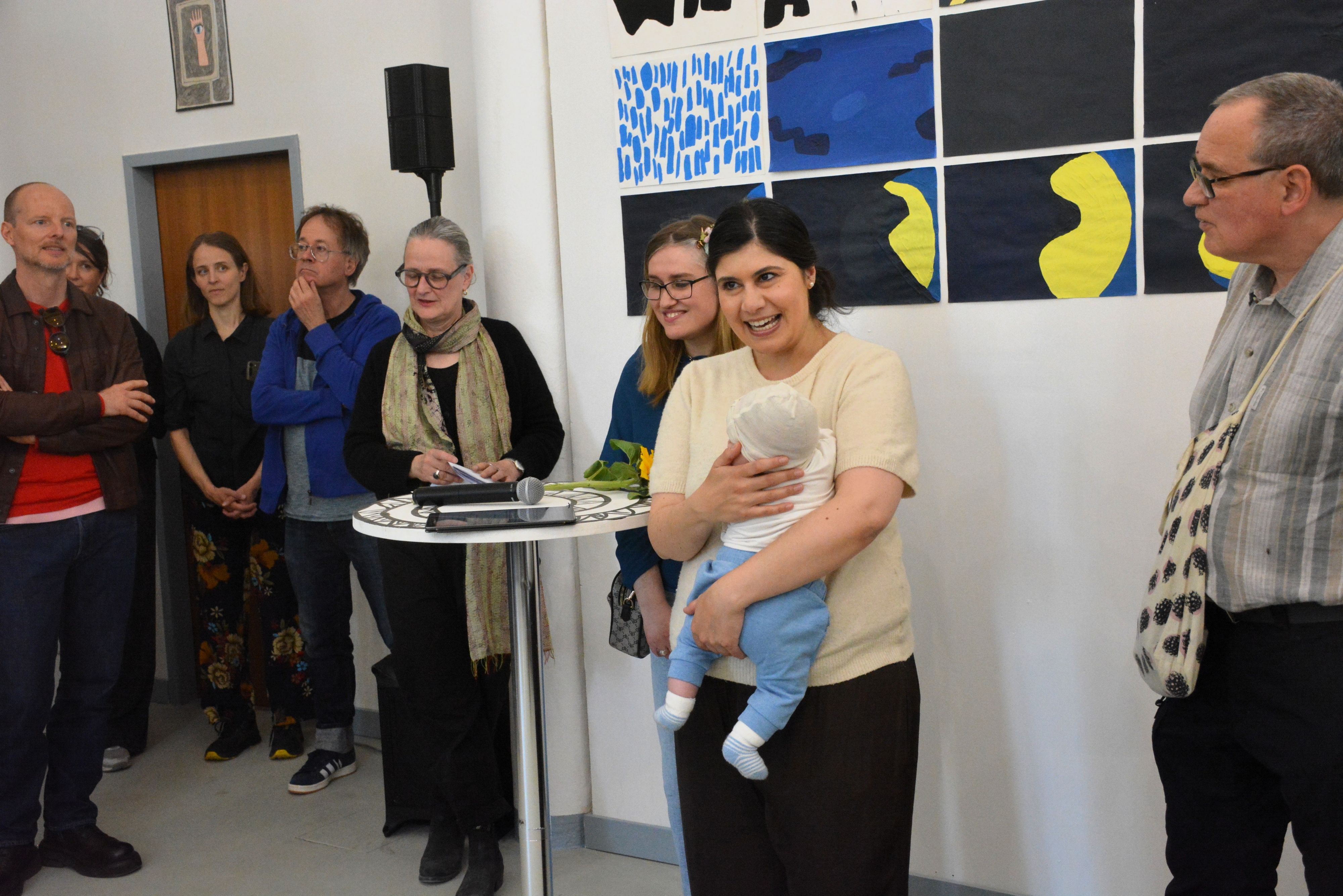 Eine Frau hält eine Rede und hält dabei ein Baby im Arm.