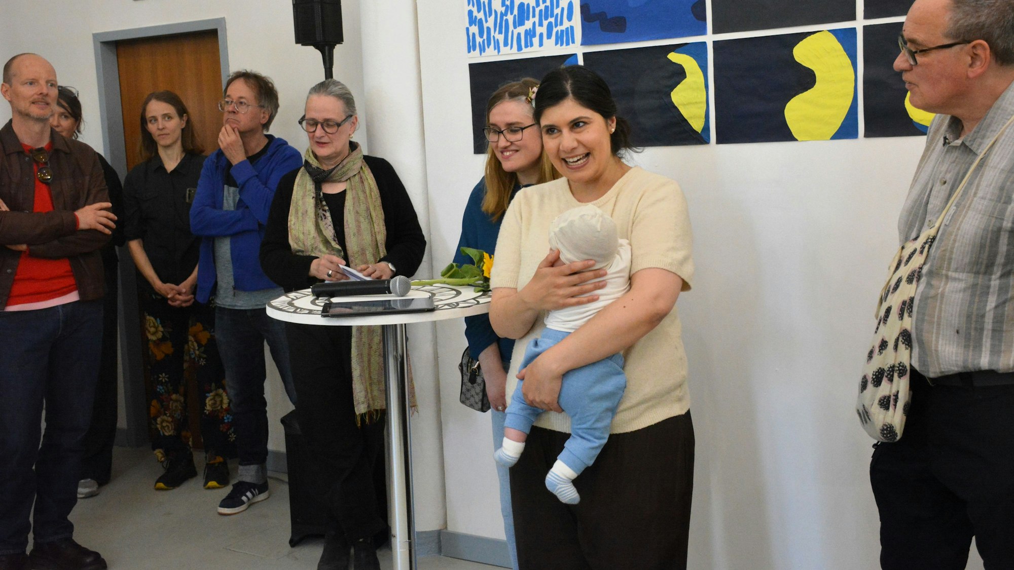 Eine Frau hält eine Rede und hält dabei ein Baby im Arm.