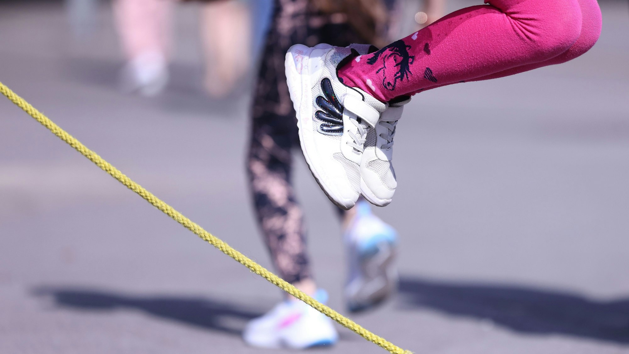 Ein Kind springt über ein Seil auf einem Schulhof.