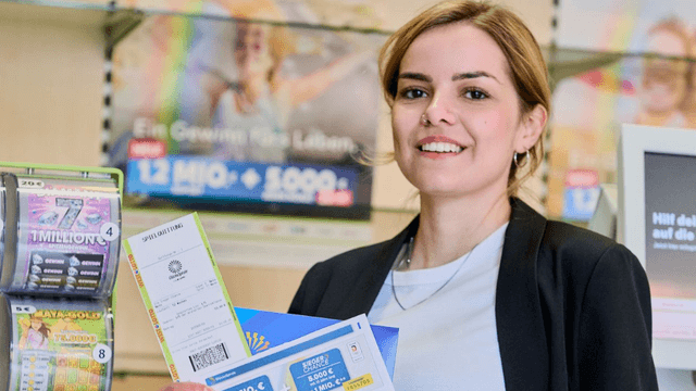 Eine Frau in einer WestLotto-Annahmestelle, die eine Spielquittung für ein Los der GlücksSpirale in der Hand hält.
