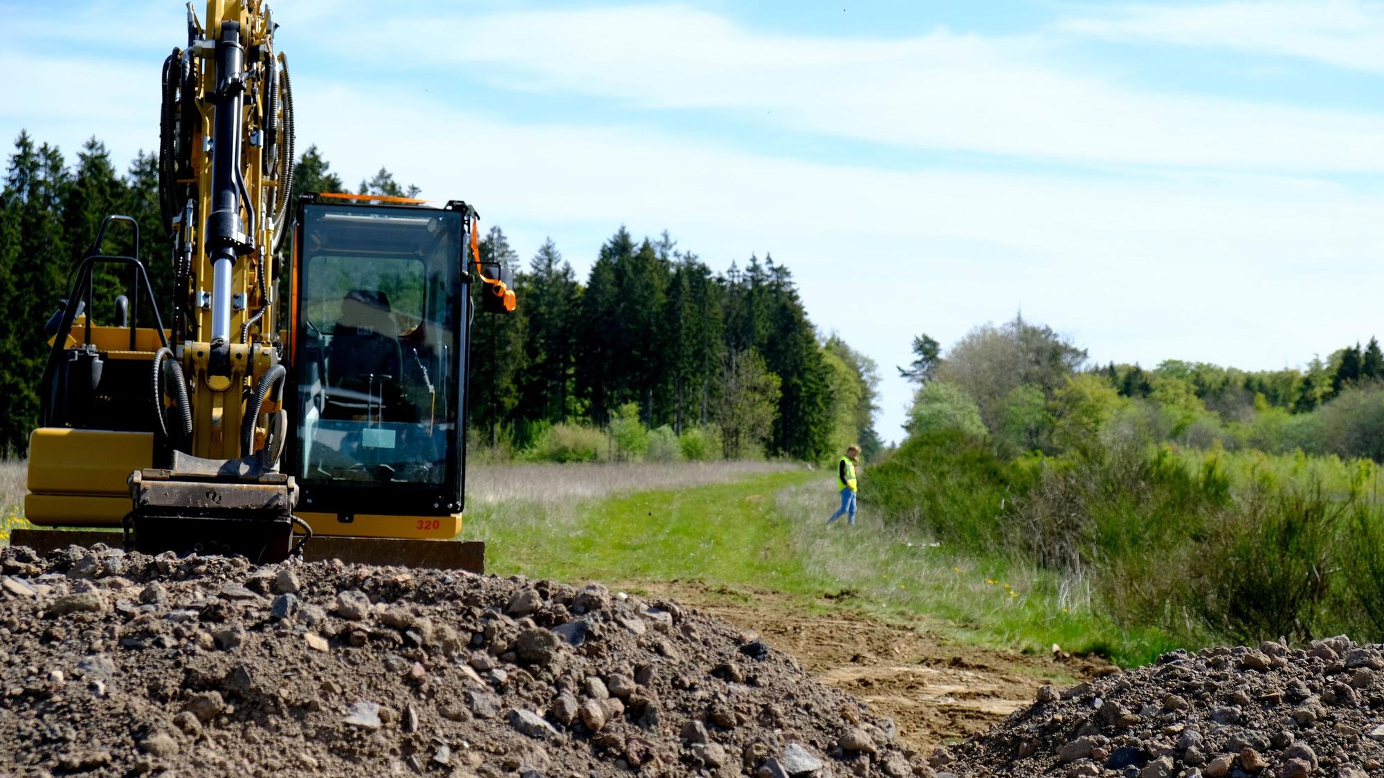 Ein Bagger an einem Erdhügel vor der künftigen A1-Trasse bei Dreis-Brück.