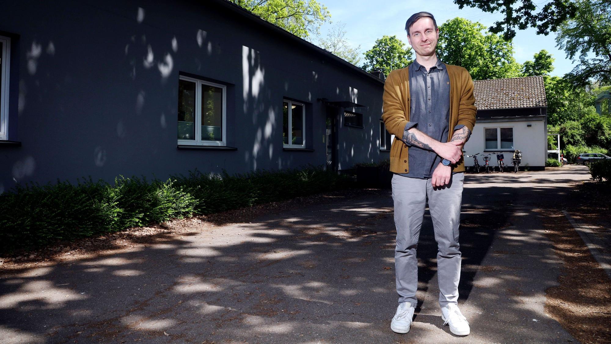 Ein Mann in beigefarbener Strickjacke schaut in die Kamera.