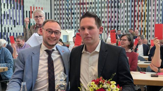 Zwei Männer sitzen an einem Tisch mit Blumen.