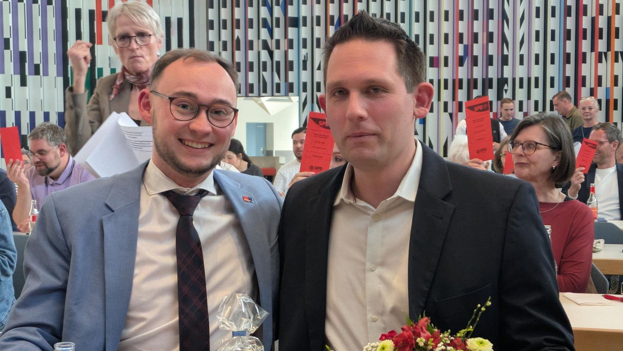 Zwei Männer sitzen an einem Tisch mit Blumen.