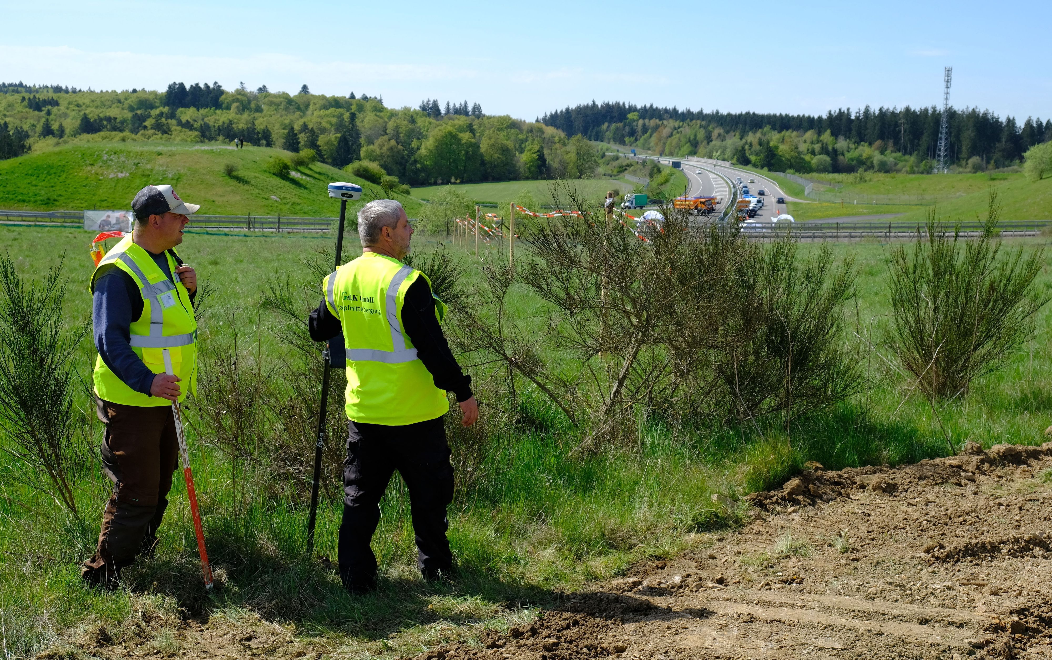 Mitarbeiter eines Kampfmittelräumers tragen gelbe Warnwesten.