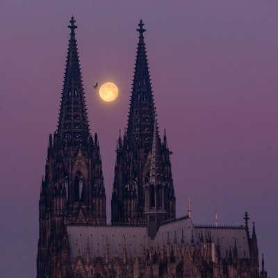 Der abnehmende Mond steht kurz vor Sonnenaufgang zwischen den Türmen des Kölner Dom. Am Freitag, 1. Mai 2026 ist wieder Vollmond. (Archivbild)