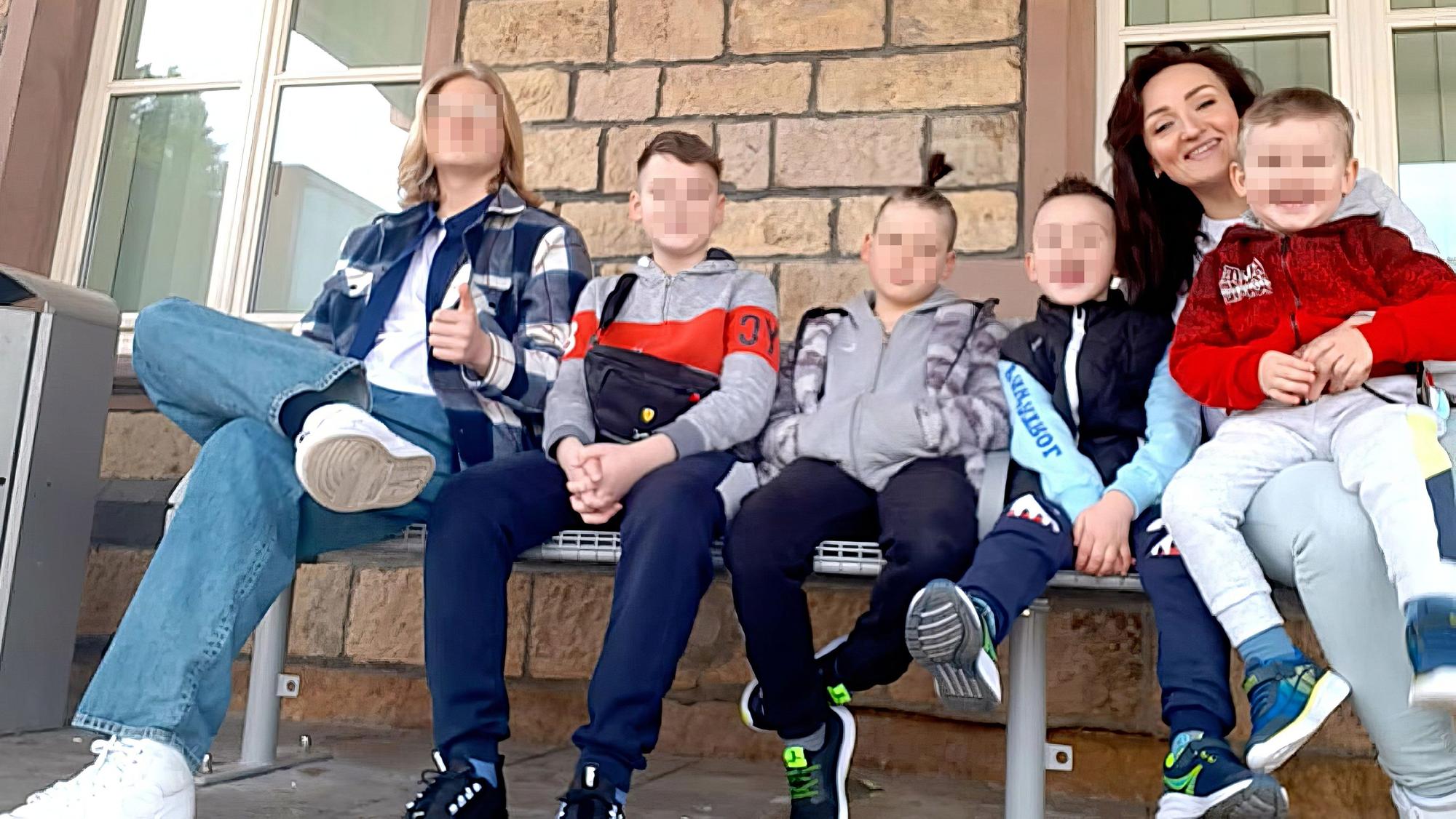 Die fünf Söhne und ihre Mutter sitzen auf einer Bank.