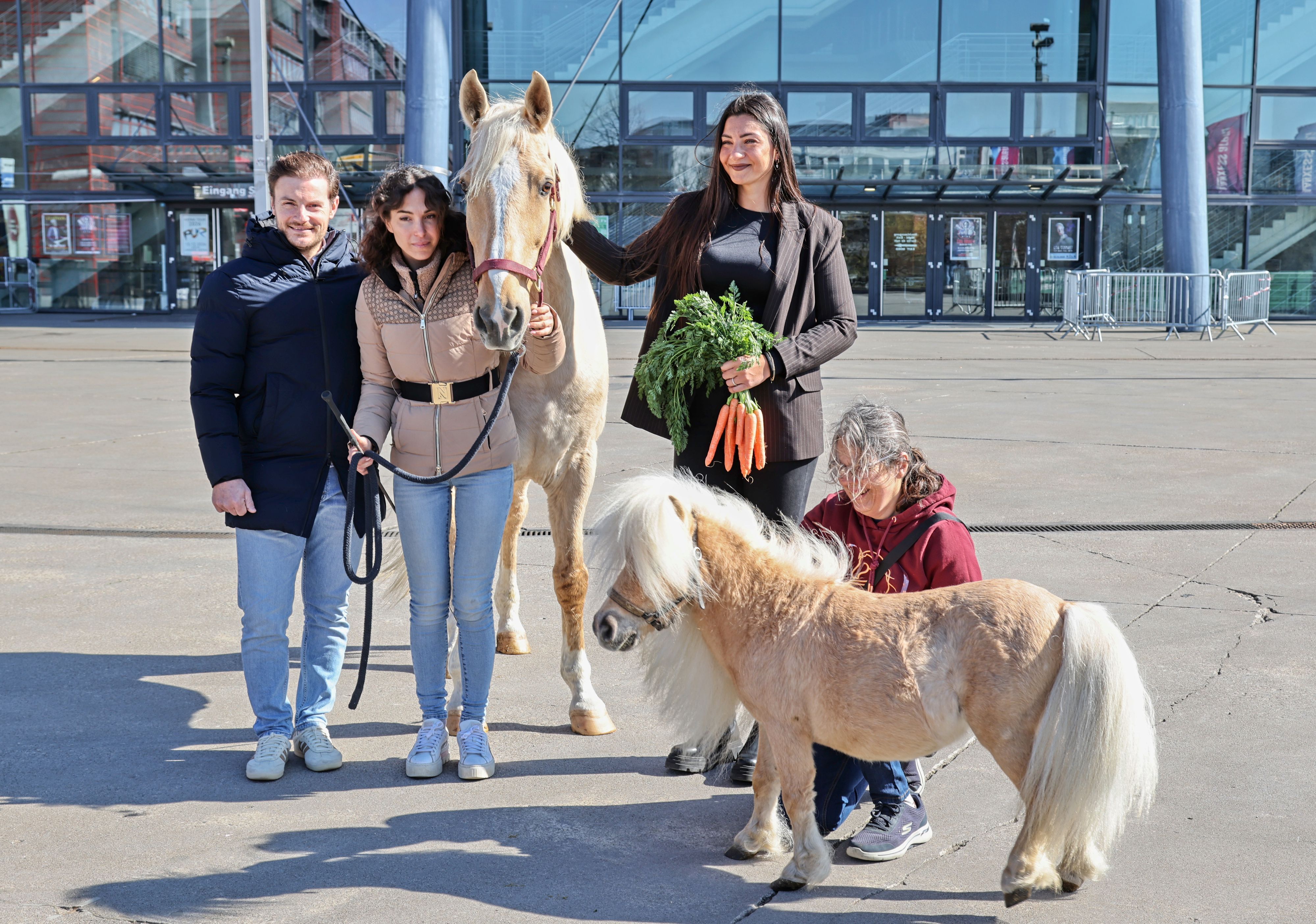 Vor der Lanxess Arena präsentierte Laury Tisseur (l.), Kenzie Dysil und Pferdepflegerin Carmen Maria Ortega Armas (2.v.r.) zusammen mit Lusitano Camillo und Mini Shetlandpony Arno die neue Show „Tor zur Anderswelt“.
