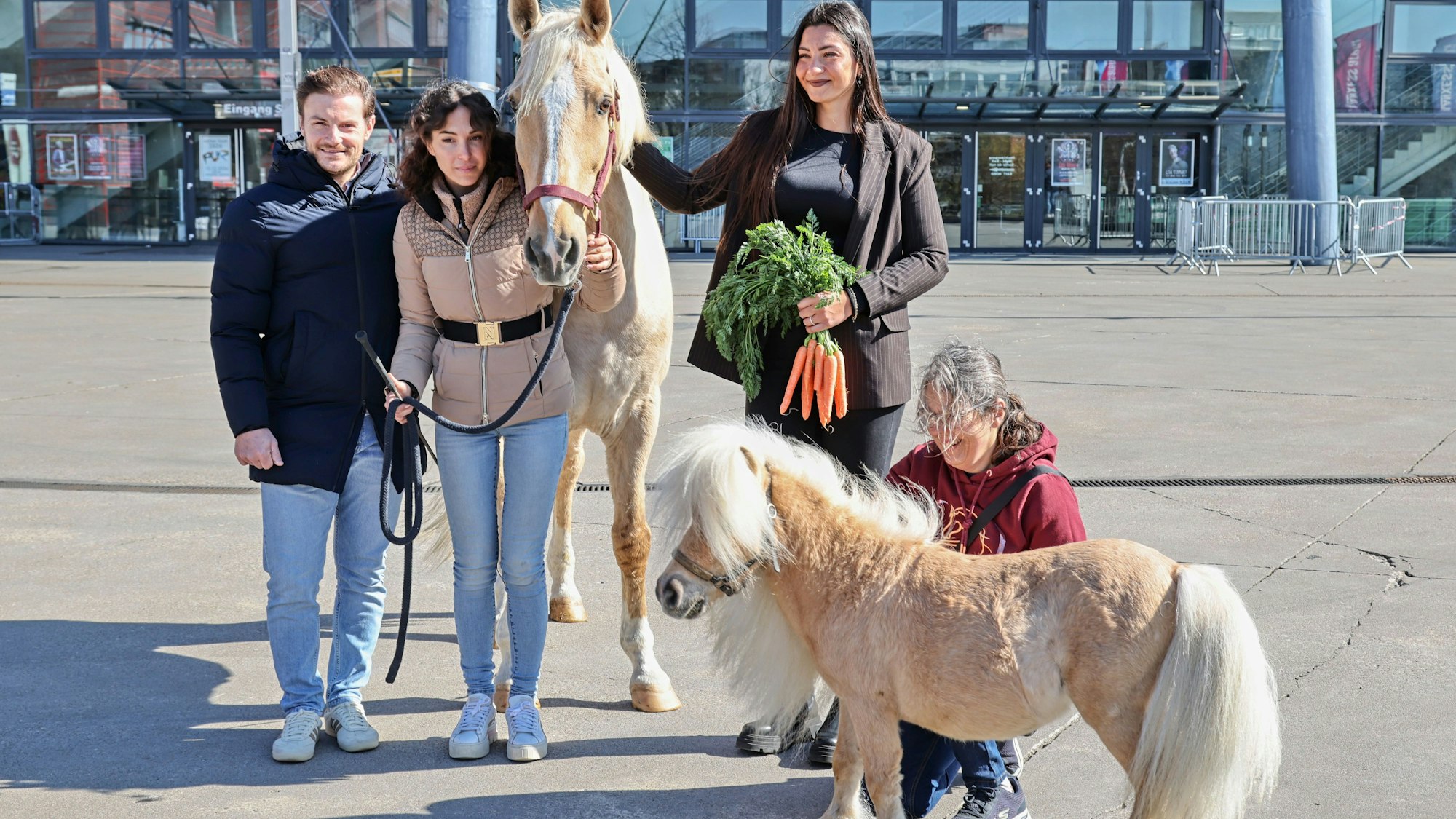 Vor der Lanxess Arena präsentierte Laury Tisseur (l.), Kenzie Dysil und Pferdepflegerin Carmen Maria Ortega Armas (2.v.r.) zusammen mit Lusitano Camillo und Mini Shetlandpony Arno die neue Show „Tor zur Anderswelt“.