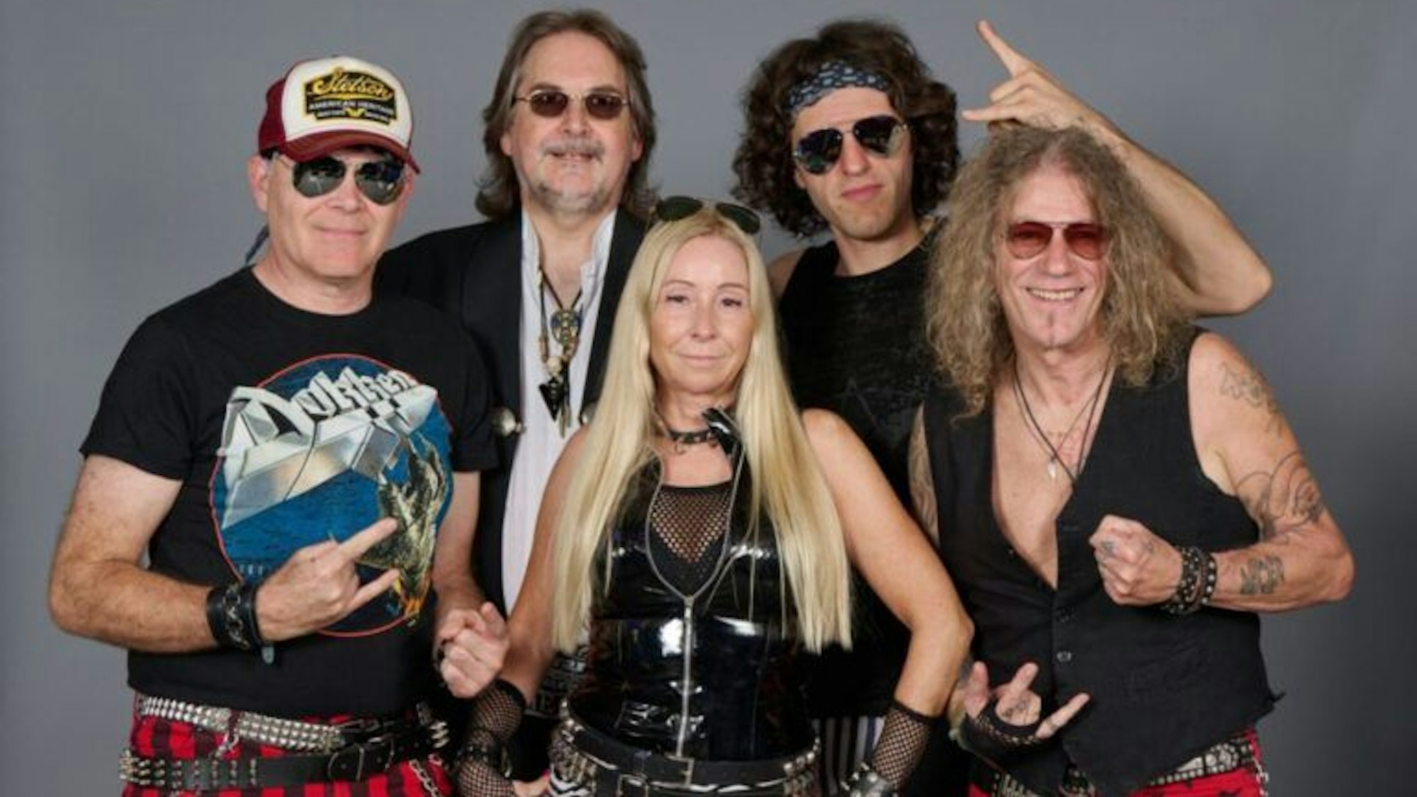 Die Musiker posieren in 80er-/90er-Outfits und blicken in die Kamera.