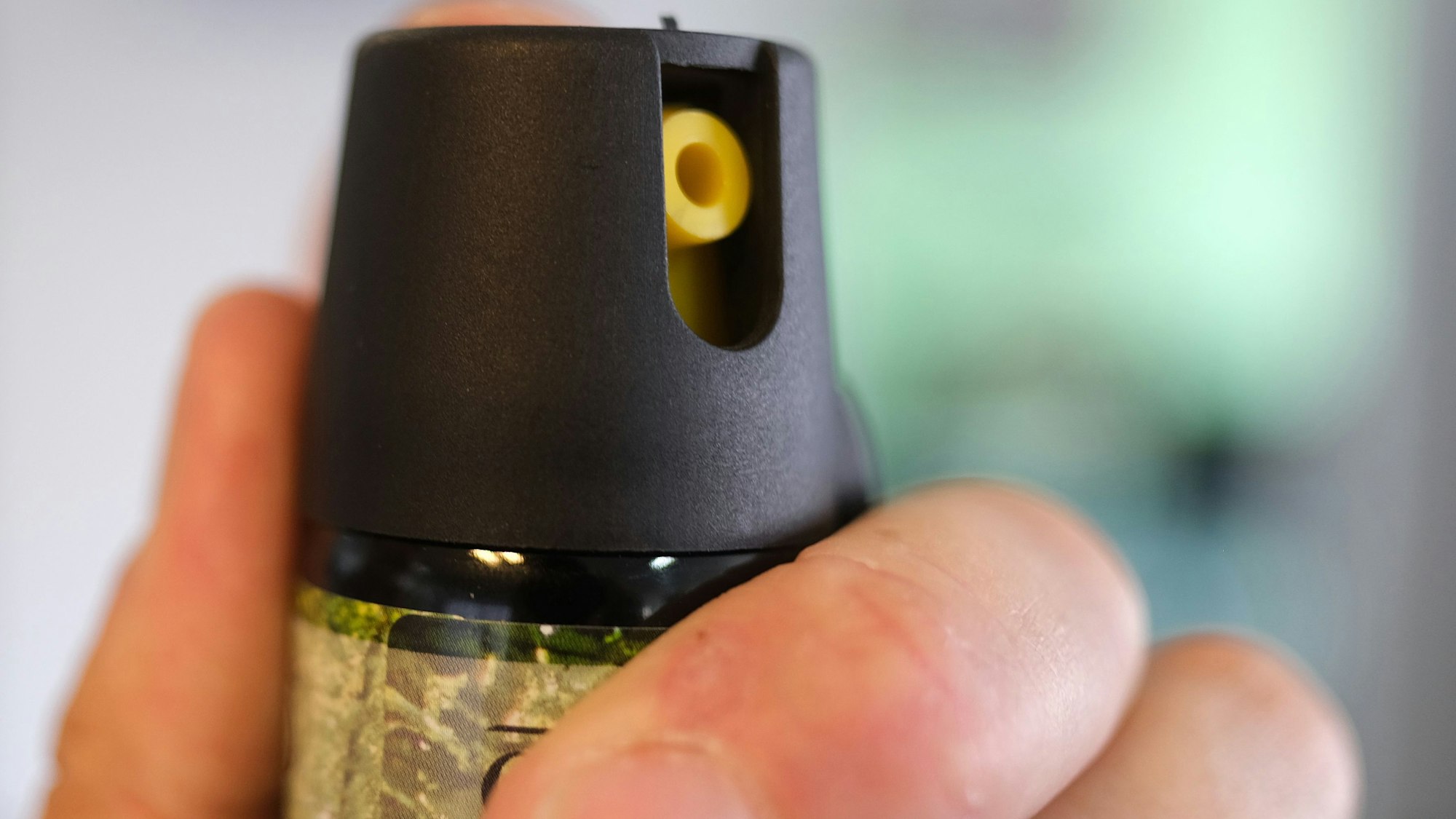 Eine Hand hält eine Kartusche mit Pfefferspray.