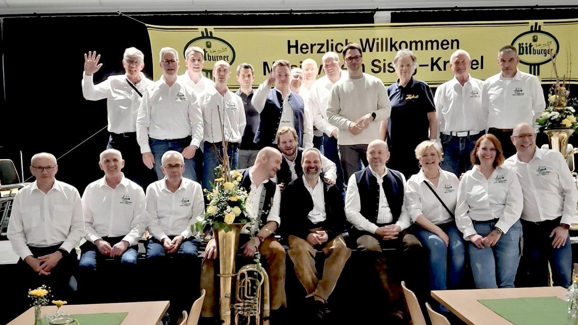 Die Musiker stehen oder sitzen auf der Bühne.
