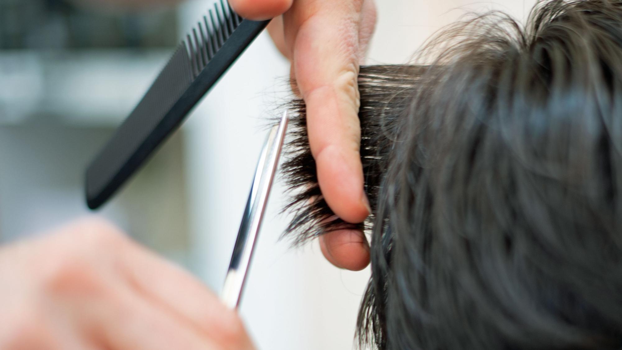 Ein Friseur schneidet in einem Friseur-Salon die Haare