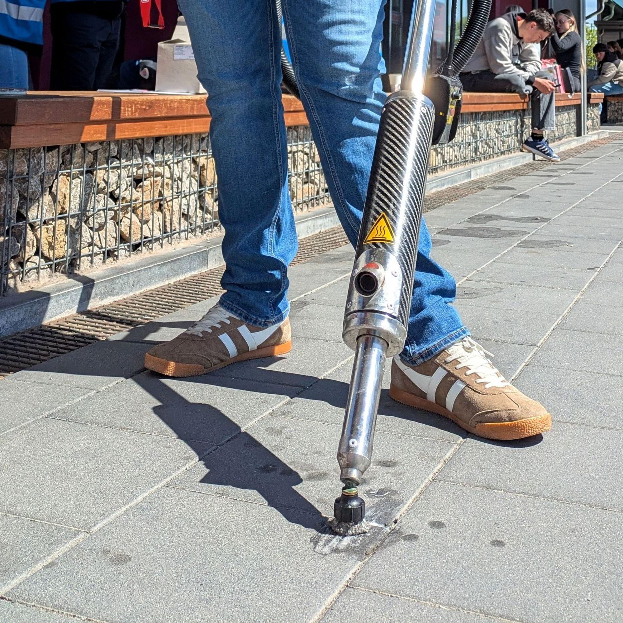 Mit einem Spezialgerät entfernt ein Mitarbeiter Kaugummireste am Mechernicher Bahnhof (Detailaufnahme).