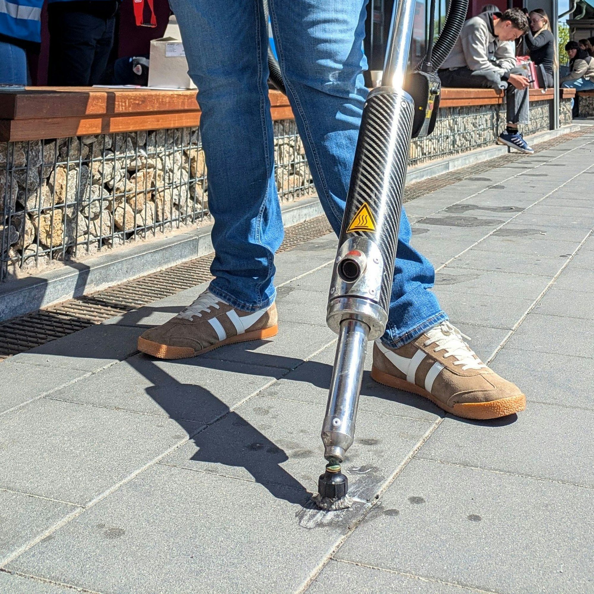 Mit einem Spezialgerät entfernt ein Mitarbeiter Kaugummireste am Mechernicher Bahnhof (Detailaufnahme).