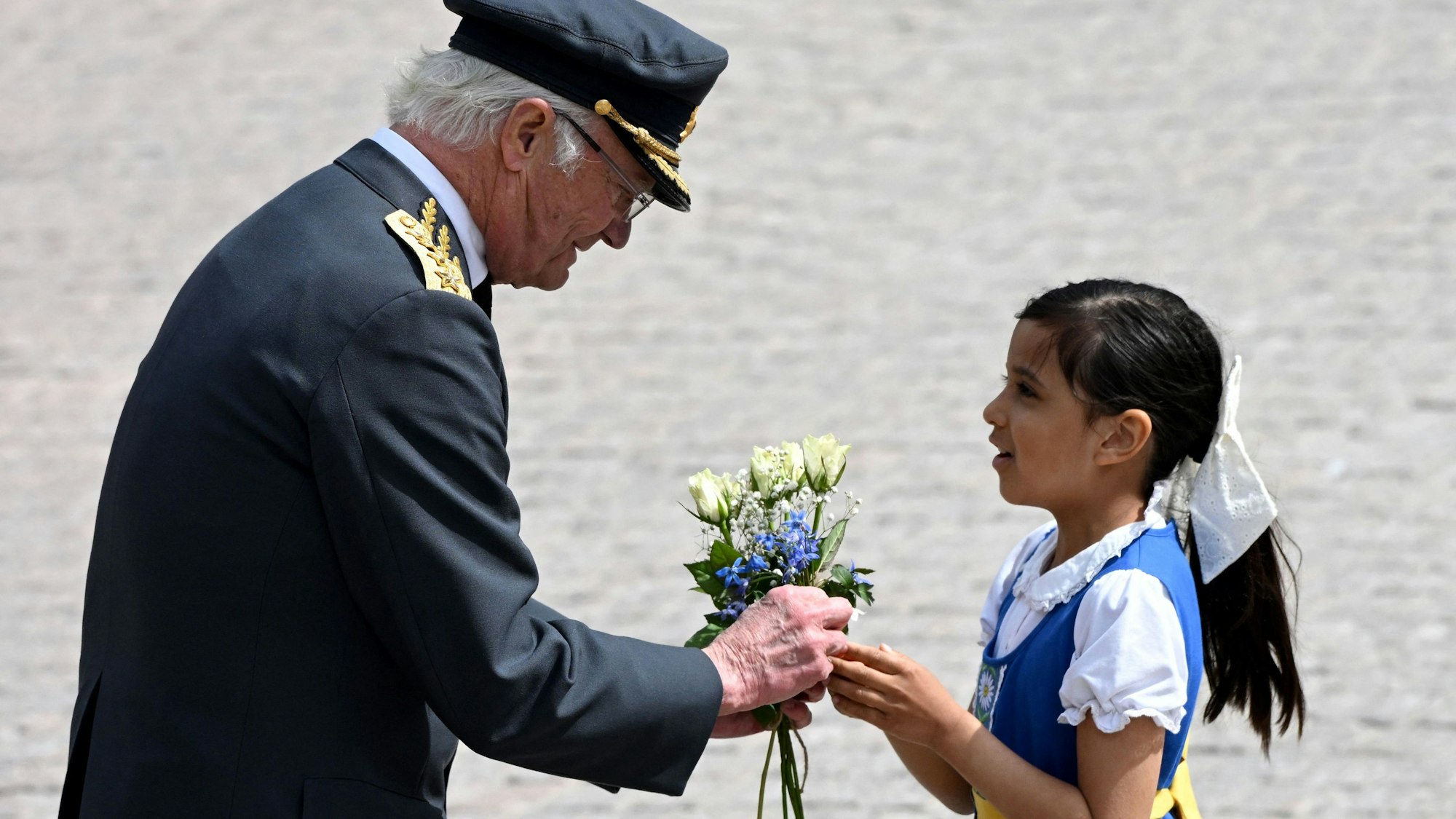 König Carl XVI. Gustaf nimmt während des Wachwechsels im Außenhof des Stockholmer Schlosses Blumen von einem Mädchen entgegen.