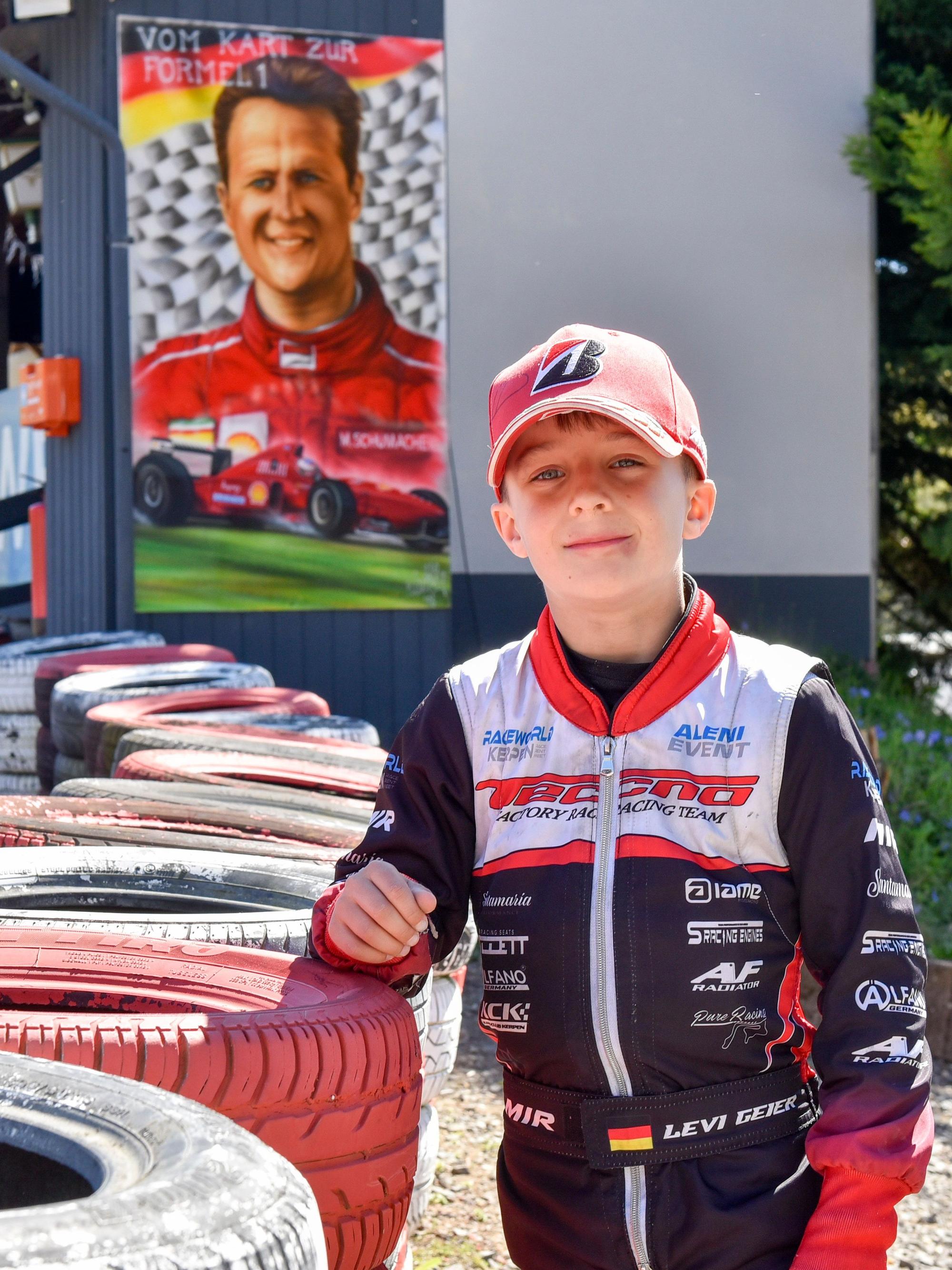 Das Foto zeigt einen Jungen vor einem Plakat von Michael Schumacher.