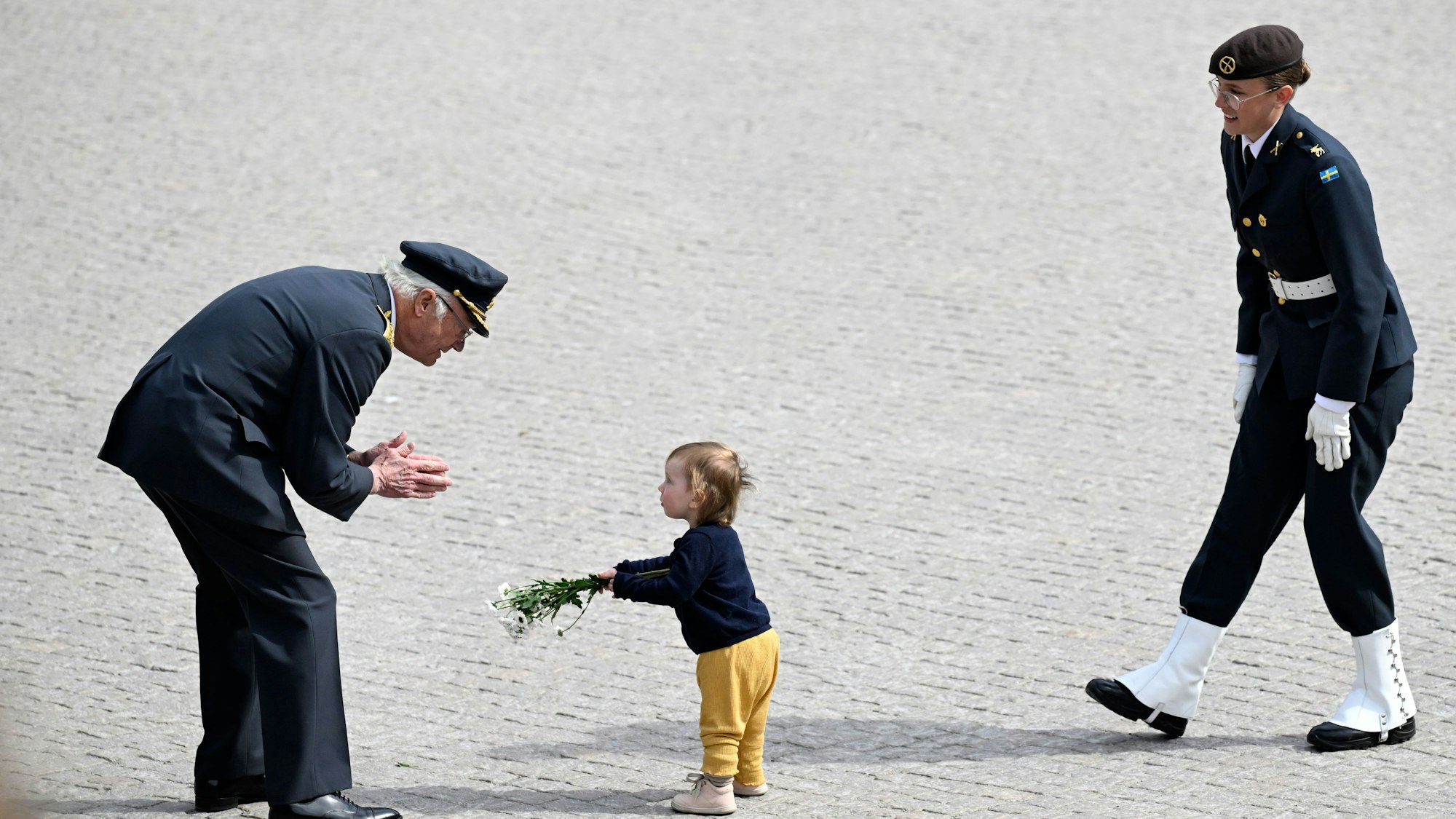 Ein Kind überreicht König Carl XVI. Gustaf Blumen während der feierlichen Ehrung durch die schwedischen Streitkräfte im Stockholmer Schloss.
