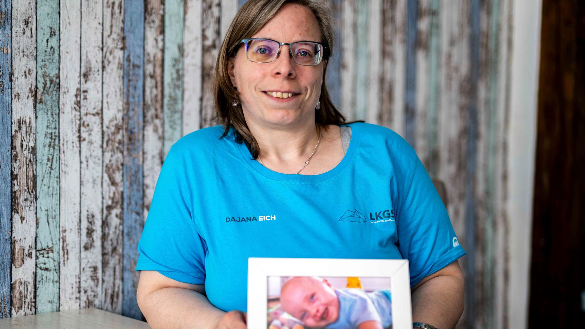 Das Bild zeigt die Großbüllesheimein, die ein Bild von ihrem Baby in die Kamera hält.