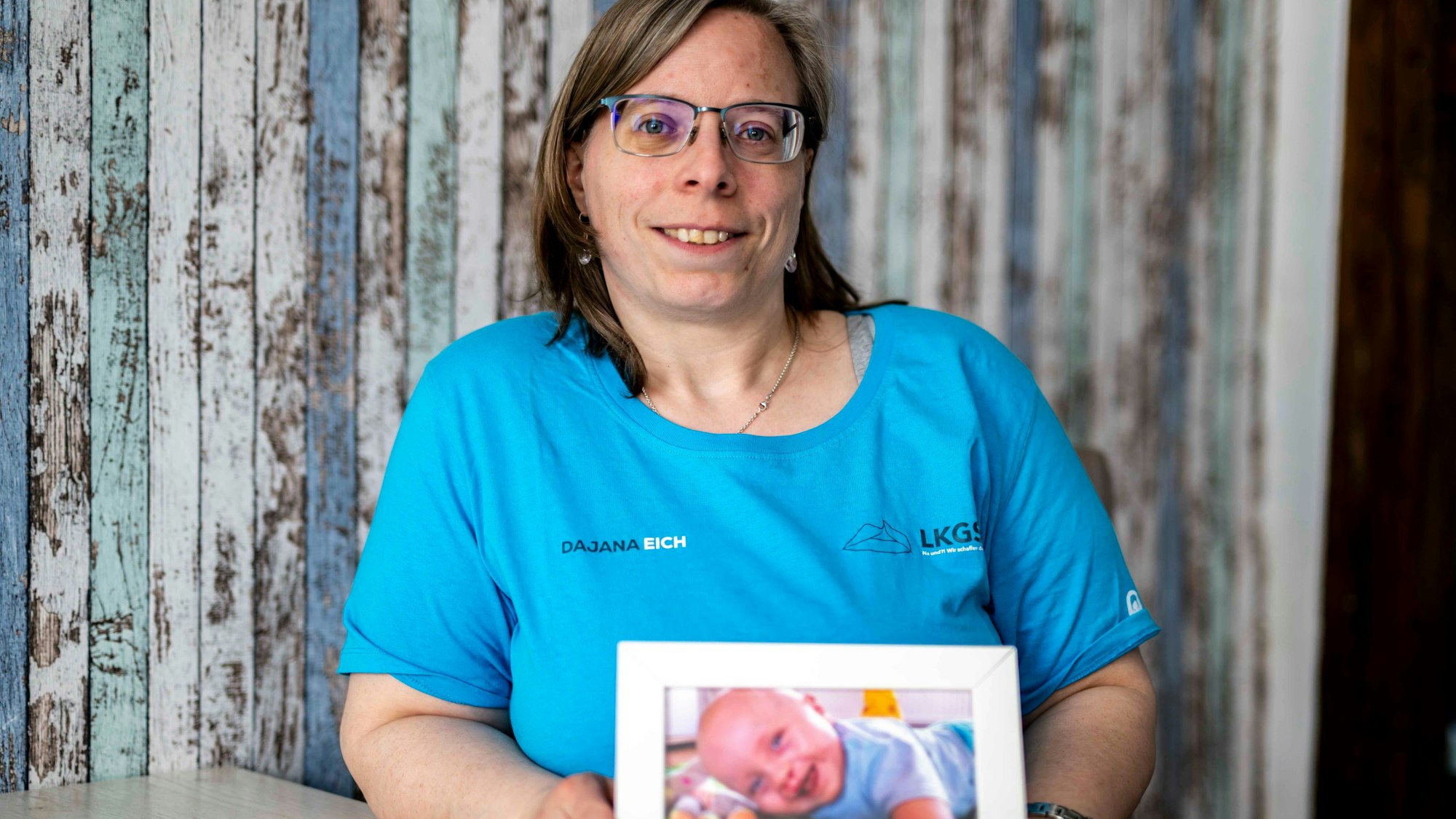 Das Bild zeigt die Großbüllesheimein, die ein Bild von ihrem Baby in die Kamera hält.