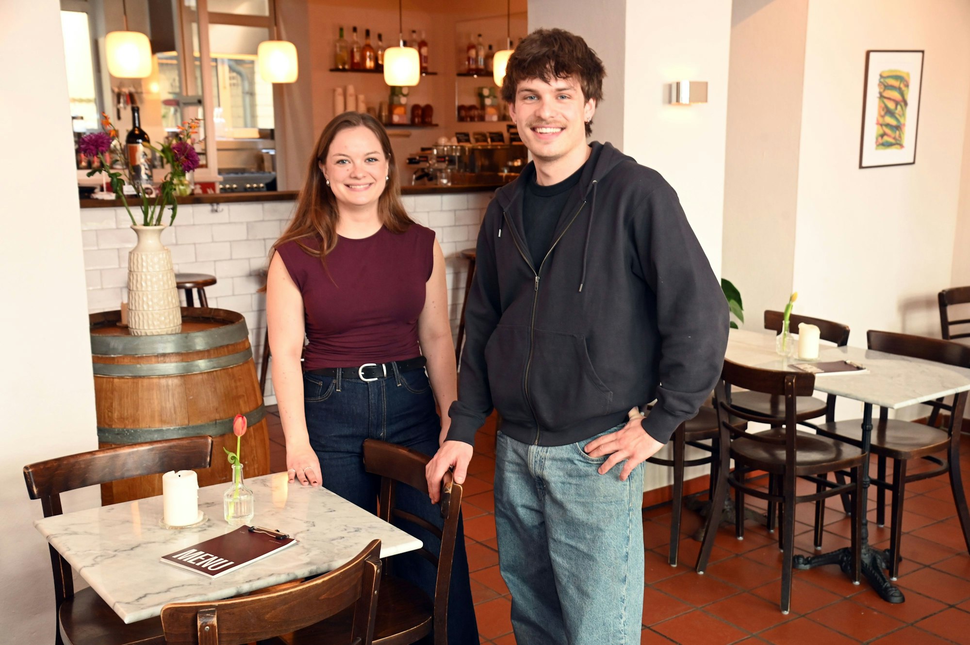 Die beiden sind im Lokal zu sehen und lächeln in die Kamera.